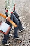 Couple walking, carrying baguette and bags, low section