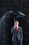 Homme d'affaires permanent sous robuste parapluie, main dans la poche
