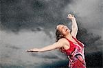Woman, arms outstretched, smiling, standing in rain