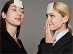 Portrait of two female office workers with sticky notes on forehead