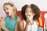 Girls using brushes, microphones to sing at a Slumber Party