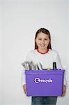 Girl (10-12) holding recycling container, smiling