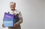 Middle-aged man holding recycling containers, smiling