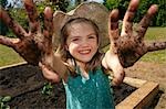 Young girl in garden with muddy hands
