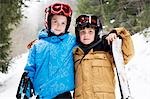 Young children hugging in snow with skis