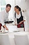 Waiter and waitress laying the table