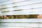 Man looks thru window blinds