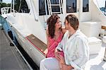 Couple assis sur le bateau au port de plaisance