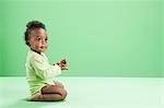 Baby boy kneeling against green background