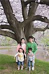 Family Leaning against Tree in Park