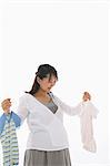 Pregnant Woman Holding Hangers of Baby Clothes