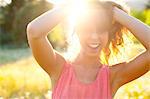 Woman with Hands in Hair in Field on Sunny Evening