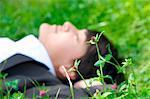 Young businessman lying in meadow