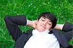 Young businessman lying in meadow