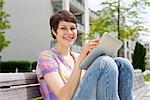 Young woman using iPad on a bench