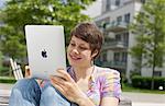 Young woman using iPad on a bench