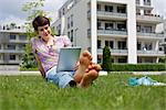 Young woman using iPad in grass