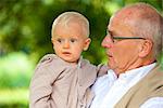 Grandfather carrying toddler outdoors, portrait