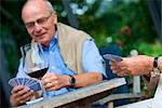 Senior couple playing cards and drinking red wine