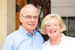 Happy senior couple in front of front door, portrait