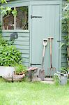 Gardening tools lean against door of potting shed