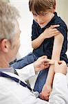 Doctor putting plaster on young boy