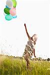 Woman with air balloons walking in field