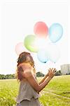 Woman with air balloons in meadows