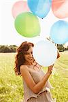 Woman holding bunch of balloons