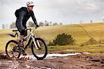 Man riding mountain bike through mud