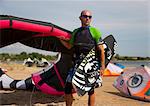 Kitesurfer holding kite and board