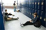 Schüler sitzen auf Boden von Schließfächern, die Nutzung von Mobiltelefonen