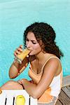 Woman drinking an apple juice by the swimming pool