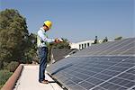 Préposé à l'entretien se tient avec des panneaux solaires sur le toit, Los Angeles, Californie