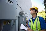 Maintenance worker reads meter of solar generation unit in Los Angeles, California