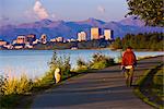 Personnes tenues de jogging, la marche et la bicyclette sur le sentier côtier de Tony Knowles avec skyline Downtown Anchorage dans le centre-sud distance, Anchorage, en Alaska, l'été