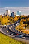 Malerischer Blick auf den Verkehr von Minnesota Blvd. entlang Westchester Lagune an einem sonnigen Tag mit der Innenstadt von Anchorage in der Ferne, South Central Alaska, Herbst