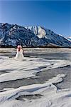 Snowman with a red scarf and black top hat sitting on the frozen Nenana River with the Alaska Range foothills in the background, Southcentral Alaska, Winter