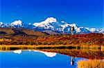 View of a couple hiking in Peters Hills with Mt. McKinley reflecting in a tundra pond, Denali State Park, Southcentral Alaska, Fall/n