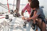 Father and son on board yacht with rope