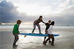 Jeunes porteurs de planche de surf, personne d'équilibrage sur le dessus