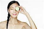 Woman holding cucumber over eye