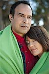 Mature couple sharing blanket outdoors, portrait