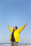 Man at the beach with arms raised in the air