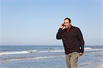 Man talking on cell phone while walking on beach