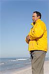 Mature homme debout sur la plage en regardant l'océan