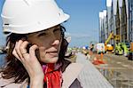 Female architect using cell phone at construction site, portrait