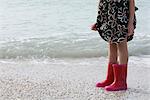 Girl standing on beach, wearing rubber boots