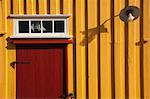 Maison jaune en bois avec porte rouge
