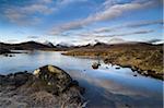 Winter view over Lochain Na h'Achlaise towards snow-covered Black Mount Hills, loch flat calm and partially frozen, reflecting blue sky and white clouds, Rannoch Moor, near Fort William, Highland, Scotland, United Kingdom, Europe